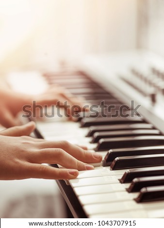 Midi keyboard or electronic piano and playing child hands. Musical education for kid in music school. Private lessons of music with a teacher for school-age children.