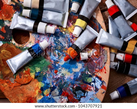 Still-life from materials on drawing. Mess of palette for mixing oil paints and tubes. Advertising courses on drawing pictures.