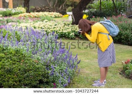 Tourist woman taking photo in flowers garden.