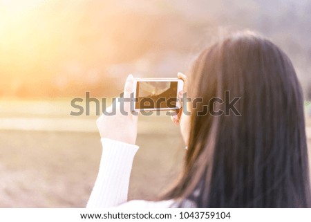 Beautiful Asian girls take pictures with their mobile phones during sunset