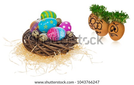 Handpainted Easter eggs in funny scared and surprised cartoonish faces with cress like hair. Handmade eggs look at the outstanding foreign individual egg in the basket. The watercress stylized