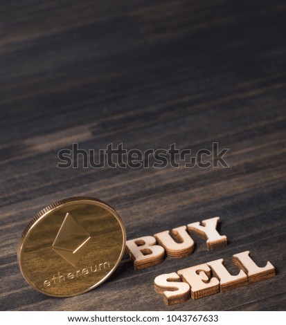 Ethereum coin crypto currency with 'BUY' and 'SELL' text on dark wooden table top