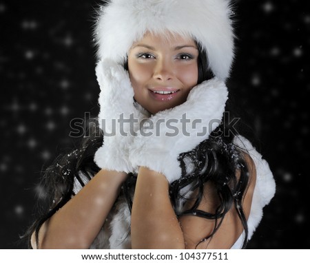 Beautiful woman in a winter hat in the snow on a black background