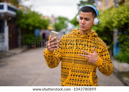 Portrait of young multi-ethnic Asian man in the streets outdoors