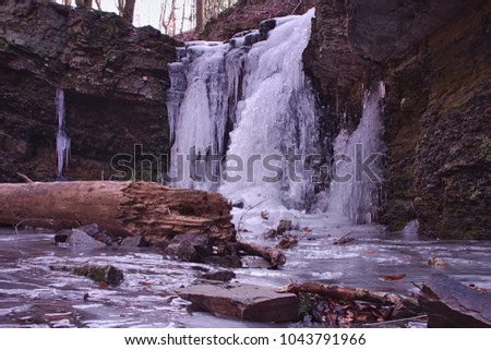 Small frozen icy creek waterfall in a forest