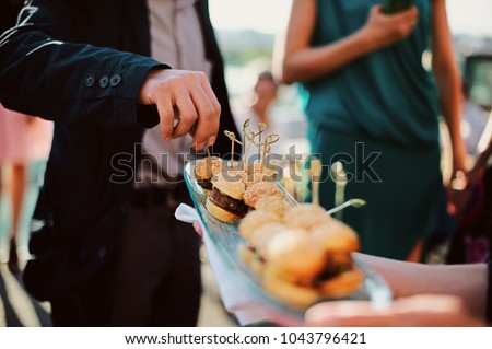 A waiter with a tray of snacks at a banquet or reception. Catering buffet at party Royalty-Free Stock Photo #1043796421