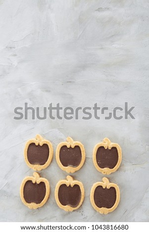Apple shaped biscuits arranged in rows on light textured background, close-up, shallow depth of field, selective focus.