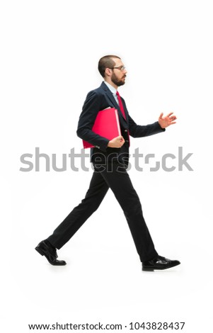 Full body or full-length portrait of businessman going with red folder on white studio background. Serious bearded young man in glasses, suit going in office. Business, career, success concept