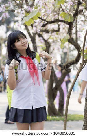 Young Beautiful Girl in white school uniform are walking and posing with smile in flower garden