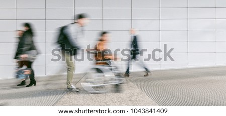 crowd of blurred people with wheelchair driver
