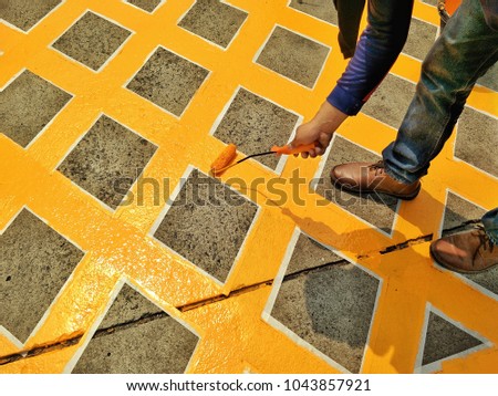 Close up of human hand and leg is painting no parking symbol with paint bucket on the parking floor in exterior decorations concept 