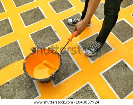 Worker's hand is painting no stopping sign on concrete floor in public area