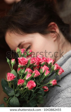 bouquet of bush of roses in female hands on a background of knitted sweaters