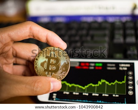 Golden bitcoin coin with mobile which show trend of price.