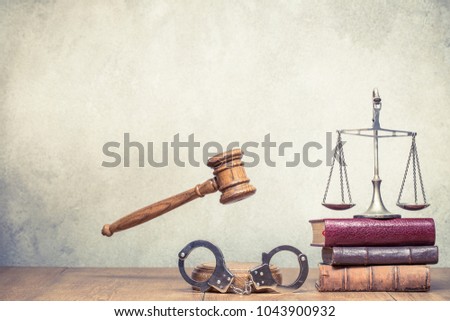 Wooden gavel, Vintage law scales, handcuffs and books on the desk front concrete wall background. Symbols of justice conceptual still life. Retro old style filtered photo