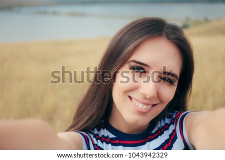 Happy Young Woman Taking a Selfie in Nature. Cute girl posing for social media in beautiful travel location

