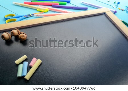 
The frame of school supplies (pencils, paints, paper, brushes, markers) on a blackboard. 