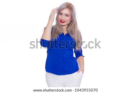 Studio business portrait of a young blonde woman in a dark blue shirt and white trousers. Girl posing on isolated white background. Smiling, looking at the camera
