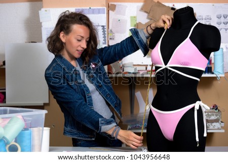 A woman dressmaker measures a mannequin with a measuring tape