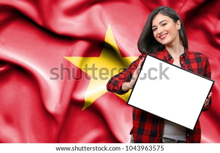 Woman holding blank board against national flag of Vietnam