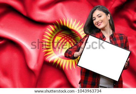 Woman holding blank board against national flag of Kyrgyzstan