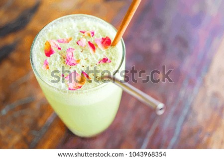 Green matcha boba or bobble tea with organic metal strobe on a wooden table with yellow flowers in a transparent vase. Chinese food in Bali restaurant. Top view with copy space.