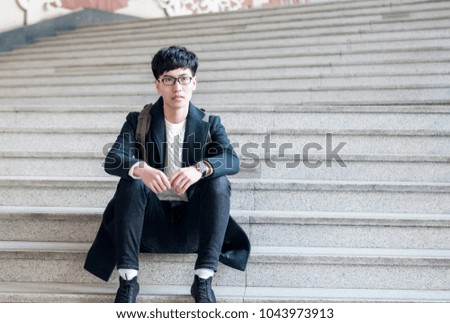The Handsome Asian man is sitting on the steps