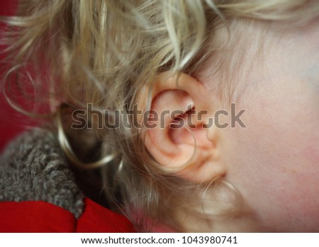 Baby girl ear and curly blond hair background. Toddler girl ear macro