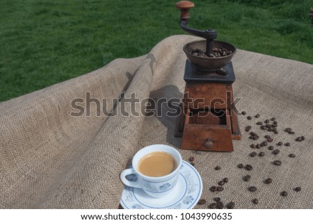 Old coffee grinder with a cup of coffee