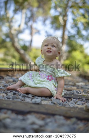 baby girl seating on a rail road track