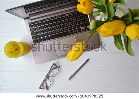 Laptop, flowers, eyewear on a white desk. Beautiful workplace top view. Office workplace.