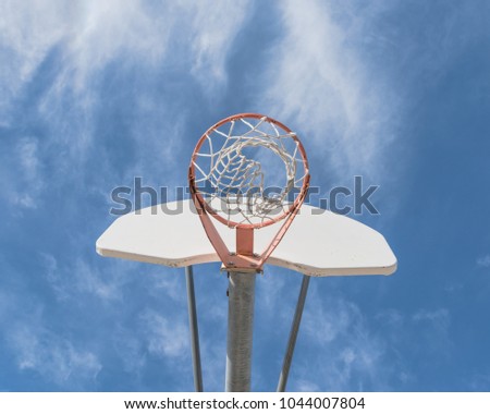 Upward view a basketball hoop in public arena at community park in Irving, Texas, USA. Lookup of rim and white backboard under cloud blue sky
