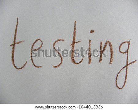 Text testing hand written by brown oil pastel on white color paper