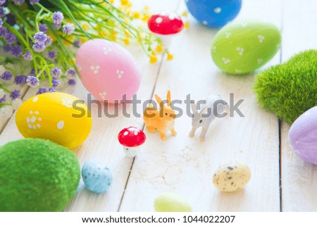 Easter eggs with flowers and small bunny toys on wooden board, easter holiday concept.