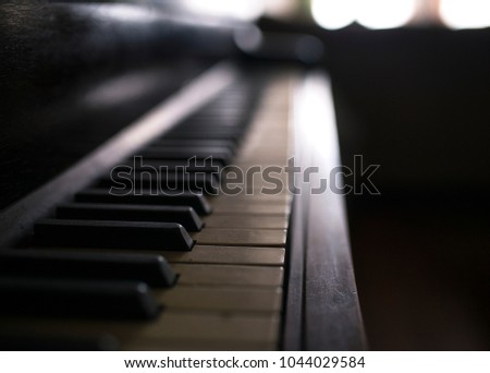 A photo of a vintage piano. The photo focuses closeup on the old keys, creating a deep bokeh blur.
