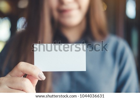 A beautiful Asian business woman holding and showing empty business card in office