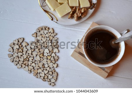 Morning coffee, tasty breakfast and decorative wooden hearts on the table. Hygge style background. 