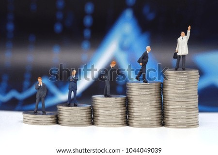 Miniature people, Businessman Team standing on coins with graph background, Picture use for business competition concept or growing coin concept.