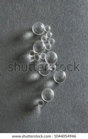 closeup  top view of industrial glass ball bearings arranged on textured grey  background with light and shade 