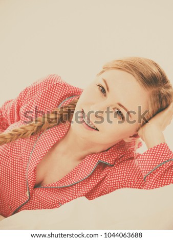 Laziness relax concept. Smiling positive teen girl in bed. Lazy youthful female wearing red dotted pajamas lying on pillow in good mood. Toned image