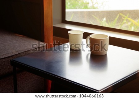 White coffee cup and plastic cup on wooden table in coffee shop