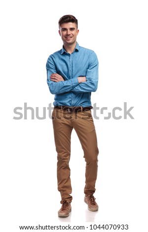 smiling young casual man standing with hands crossed on white backgrouond, full body picture