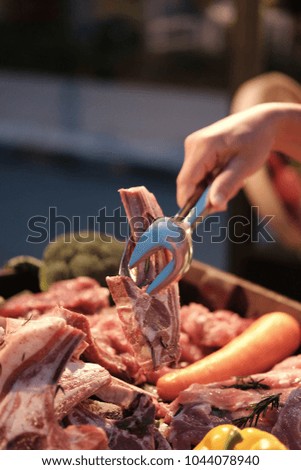 Steakr on a plate held at a buffet with hand holding a spoon of stuffed mushrooms from dish - selective focus