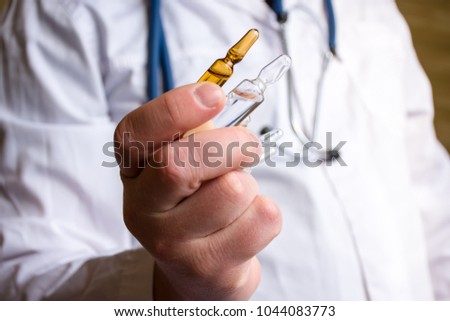 Doctor in medical lab coat holding pharmaceutical vials or ampoule of medicine, offering them patient  on blurred background. Treatment with drug in ampoules via intramuscular or intravenous injection Royalty-Free Stock Photo #1044083773