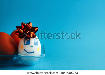 festive egg with bow and smile, on blue background .close up.