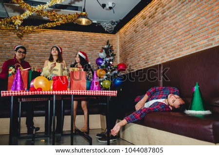 picture of Asian man are very drunk and sleeping on the couch with his friend are drinking champagne at the party. concept of Xmas party, Christmas party and New year party celebration.