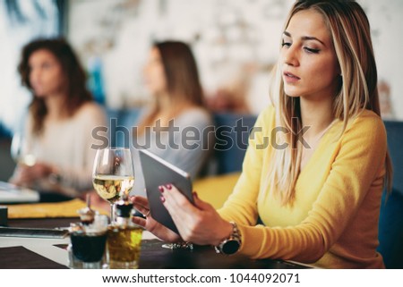 Young caucasian woman using tablet while sitting in cafe and drinking coffee.