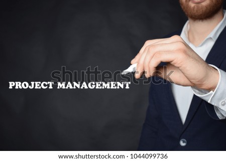 The businessman writes an inscription with a white marker:PROJECT MANAGEMENT