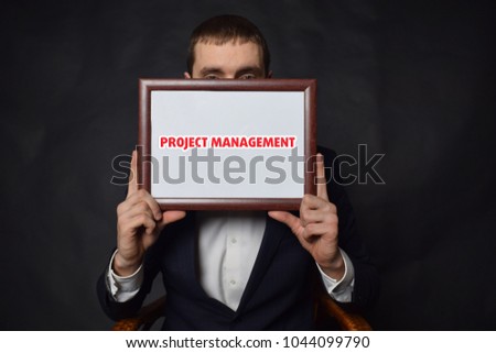 In the hands of a businessman a frame with the inscription:PROJECT MANAGEMENT