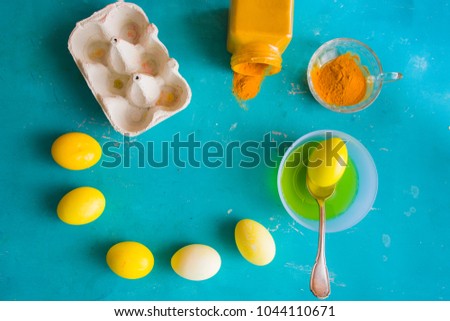 Dyeing eggs for Easter holidays,using natural ingredients curcuma to create a yellow tonality over a blue concrete background